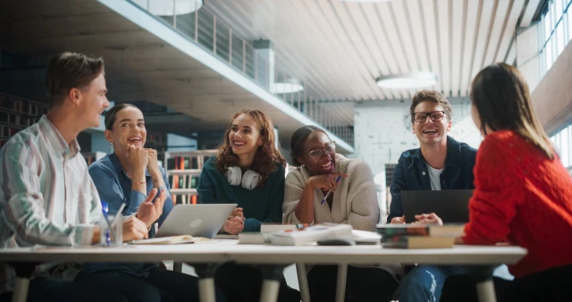 Group of students sitting at a round table talking to each other